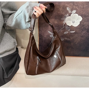 Detail of dark brown vintage tote bag featuring decorative zippers and adjustable strap