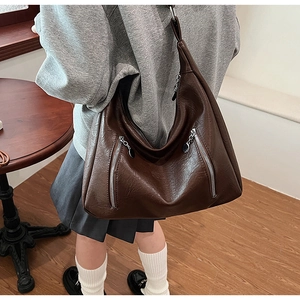 Close-up of deep brown vintage tote bag with decorative diagonal zippers and soft texture