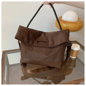 Macro shot of brown suede tote bag featuring a twisted rope handle on a glass coffee table