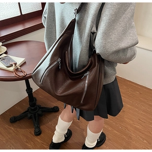Detail view of large dark brown leather hobo bag with silver zipper accents and chain strap