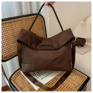 Detail of vintage brown suede tote bag with braided handle on a rattan chair
