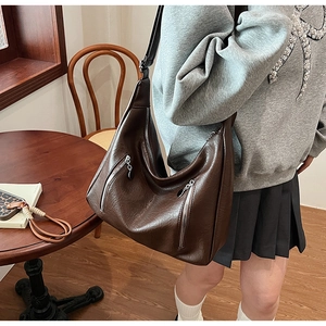 Detail of vintage brown leather hobo bag with silver zippers and adjustable strap