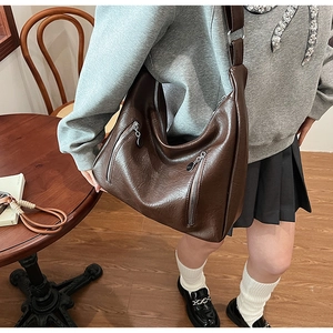Detail of vintage dark brown tote bag with premium leather texture and silver zippers