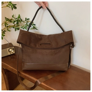 Detail of vintage brown tote bag showing suede and PU leather patchwork with woven handles