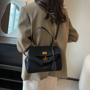 Sac à main rétro noir mat avec fermoir doré et bandoulière porté par un mannequin