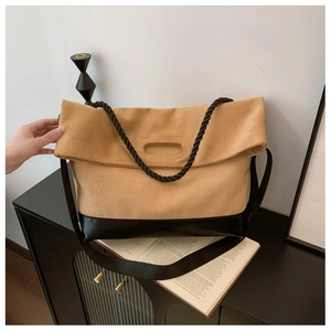 Detail view of large beige suede tote bag with rope handles and black leather trim bottom