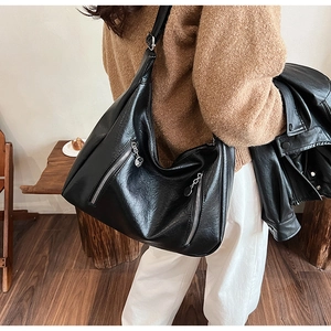 Detail of black textured leather Hobo bag with silver zippers and round metal charms