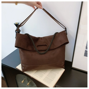 Detail of dark brown tote bag with suede stitching and decorative braided rope elements