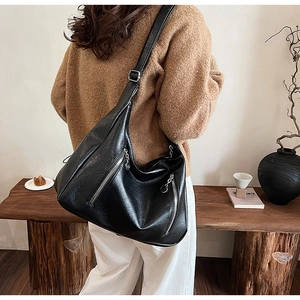 Detail view of black textured PU leather tote bag with silver zipper and adjustable strap