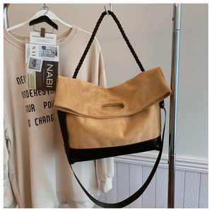 Detail of camel suede tote bag with black woven handle and contrast base panel