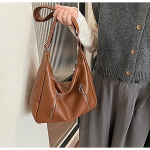 Detail of caramel brown PU leather crossbody bag with dual silver zippers and wide strap