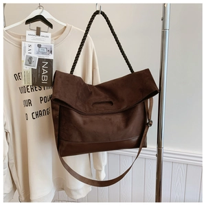 Detailed view of dark brown suede tote bag with woven rope handle and adjustable strap