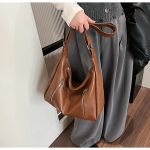 Detail of brown faux leather hobo bag featuring silver zippers and pebbled texture