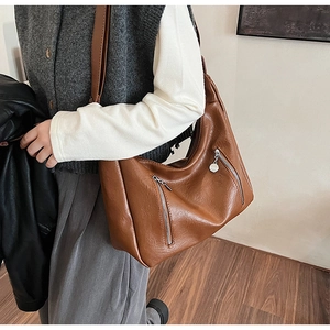 Detailed view of brown faux leather tote showing silver zippers and retro texture