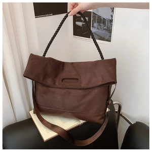 Detail of coffee brown suede tote bag featuring a black twisted handle and nylon strap