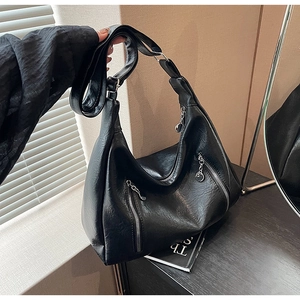 Detail of black matte PU hobo bag featuring vertical silver zippers and a wide shoulder strap