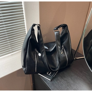 Close-up of black litchi pattern PU leather tote bag with silver zippers and metal charms