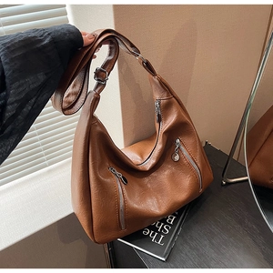 Detail of brown crescent bag featuring litchi grain PU leather and zip pockets