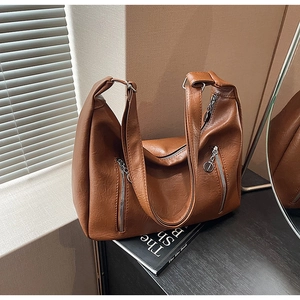 Detail of caramel brown PU leather shoulder bag with textured surface and dual zip pockets