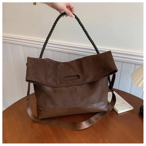 Detail of dark brown tote bag showing matte suede texture and black twisted rope handles