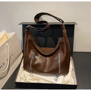 Detail of a dark brown glossy hobo bag with silver zippers in a premium gift box