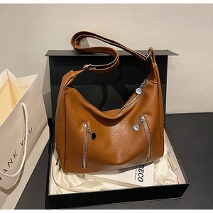 Detail of dark brown vintage dumpling bag with zip pockets inside a black gift box