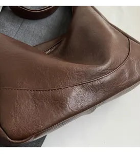 Detail of soft dark brown pebble leather tote bag with silver zipper and fine stitching