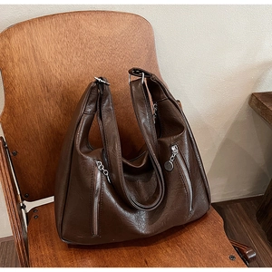 Close-up of vintage brown leather tote bag showing wax texture and silver zipper detail