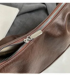 Close-up of a smooth silver metal zipper on a premium brown leather tote bag