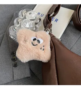 Star-shaped plush charm with a smiley face hanging on a brown leather tote bag