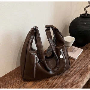 Detail shot of deep brown PU leather tote bag with silver zipper and rustic wooden background