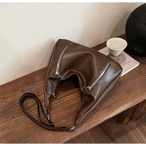 Detailed view of dark brown vintage tote bag with silver zippers on a wooden bench