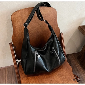 Detail of black PU leather hobo bag with dual vertical silver zippers on vintage chair