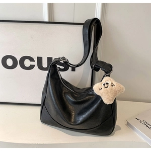 Detail of black semi-circle tote bag with silver zipper and yellow star plush charm
