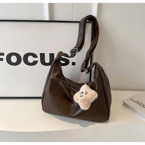 Detail of dark brown PU leather hobo bag with adjustable strap and plush charm