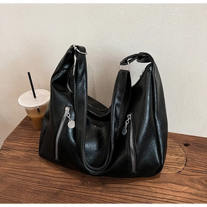 Detailed view of the black wrinkled faux leather texture and silver zippers on a tote bag