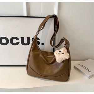 Detail of brown PU leather tote bag featuring a cute beige plush star charm and Hobo style