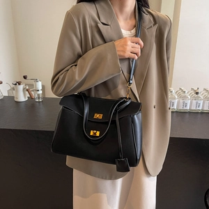 Sac à bandoulière en suédine noire avec fermoir doré en situation de mode urbaine