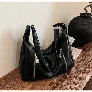 Detail of black PU leather tote bag with lychee texture and twin front zipper pockets