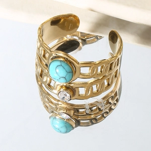 Macro detail of golden Cuban link ring featuring a turquoise bead and clear zircon crystal