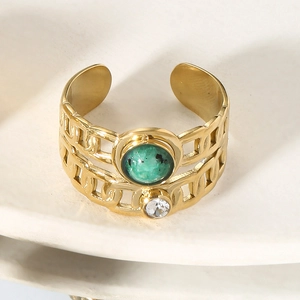 Close-up of retro gold open ring with green stone, cubic zirconia and chain link design