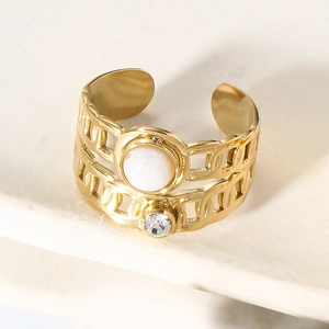 Macro shot of gold wide curb link ring with white natural stone and round zircon inlay