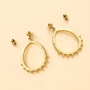 Vue détaillée de boucles d'oreilles goutte dorées avec bordure perlée et fermoirs papillon