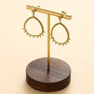 Détail de boucles d'oreilles goutte dorées 14K avec bordure perlée sur support