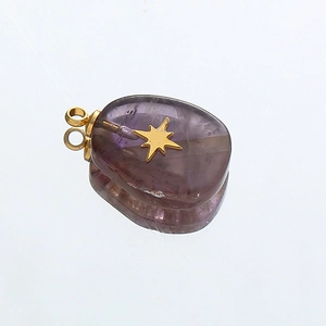 Macro shot of purple semi-transparent stone pendant with golden star inlay and bail