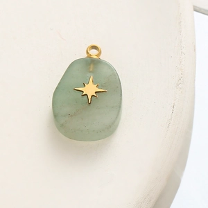 Macro shot of light green natural stone pendant with a gold star inlay and metal hook