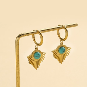Boucles d'oreilles bohèmes en triangle doré avec turquoise sur un porte-bijoux