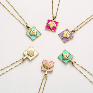 Detail showing six colorful enamel square necklaces with golden shell relief on a white surface