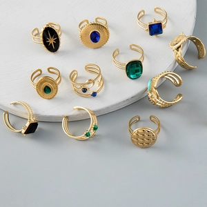 Set of 11 vintage gold adjustable rings with colorful gemstones on a marble platform