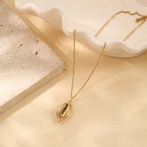 Detailed close-up of a gold-plated seashell pendant necklace on a warm marble surface